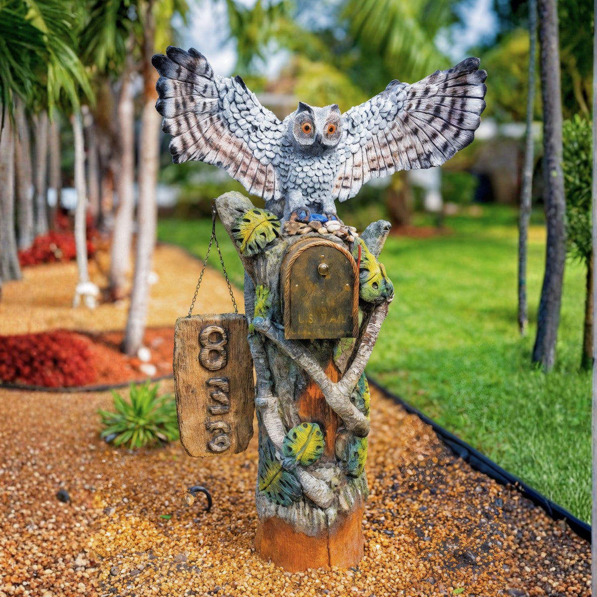 Owl mailbox sculpture with wings spread over a carved tree trunk post