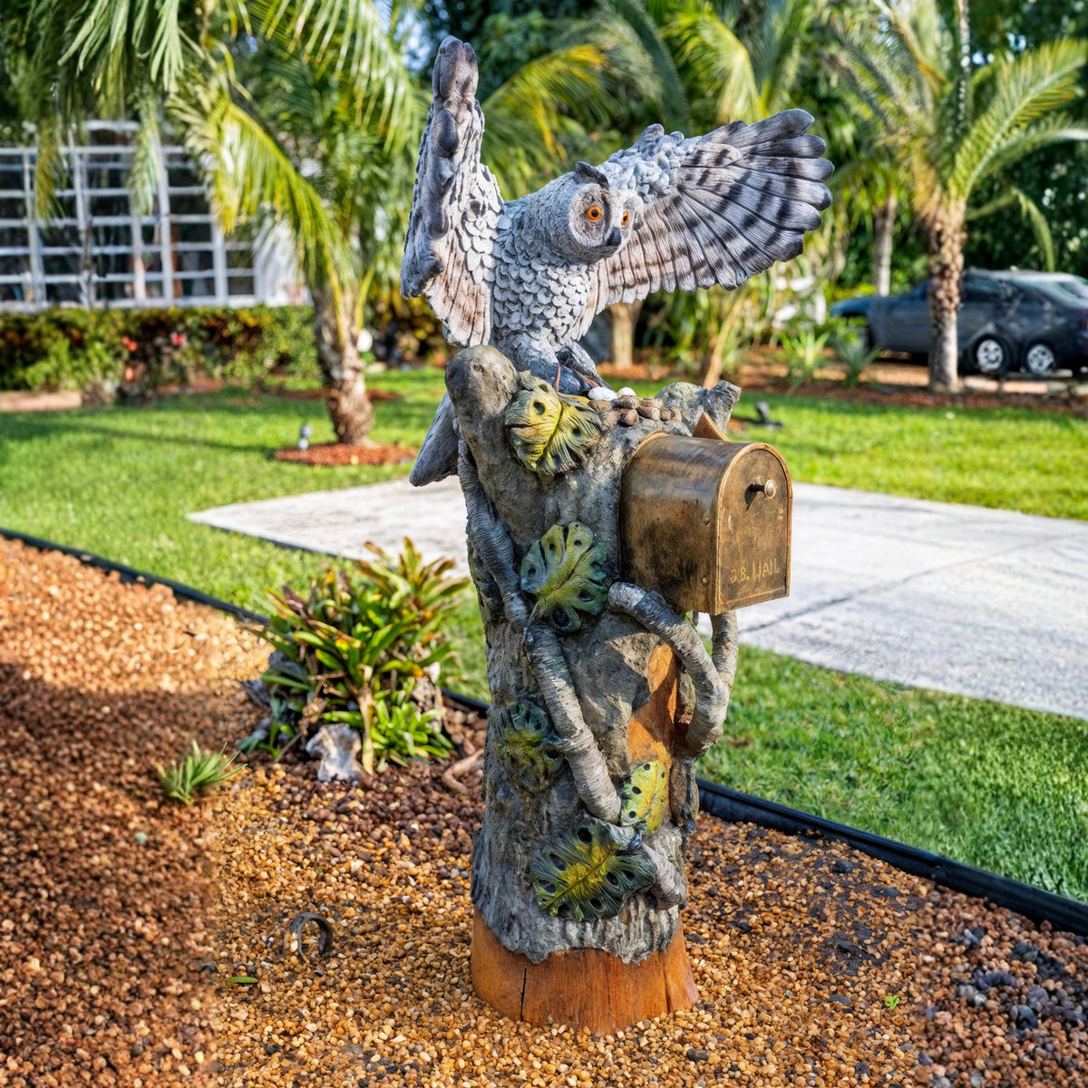 Spread wing owl mailbox sculpture in a tropical front yard
