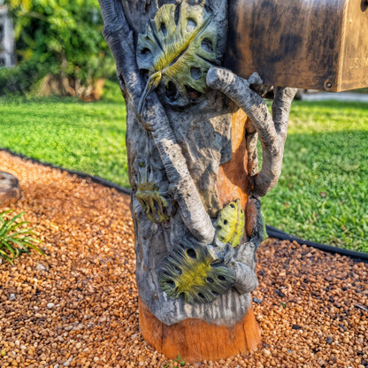 Close-up of carved leaves and branches on owl mailbox sculpture post