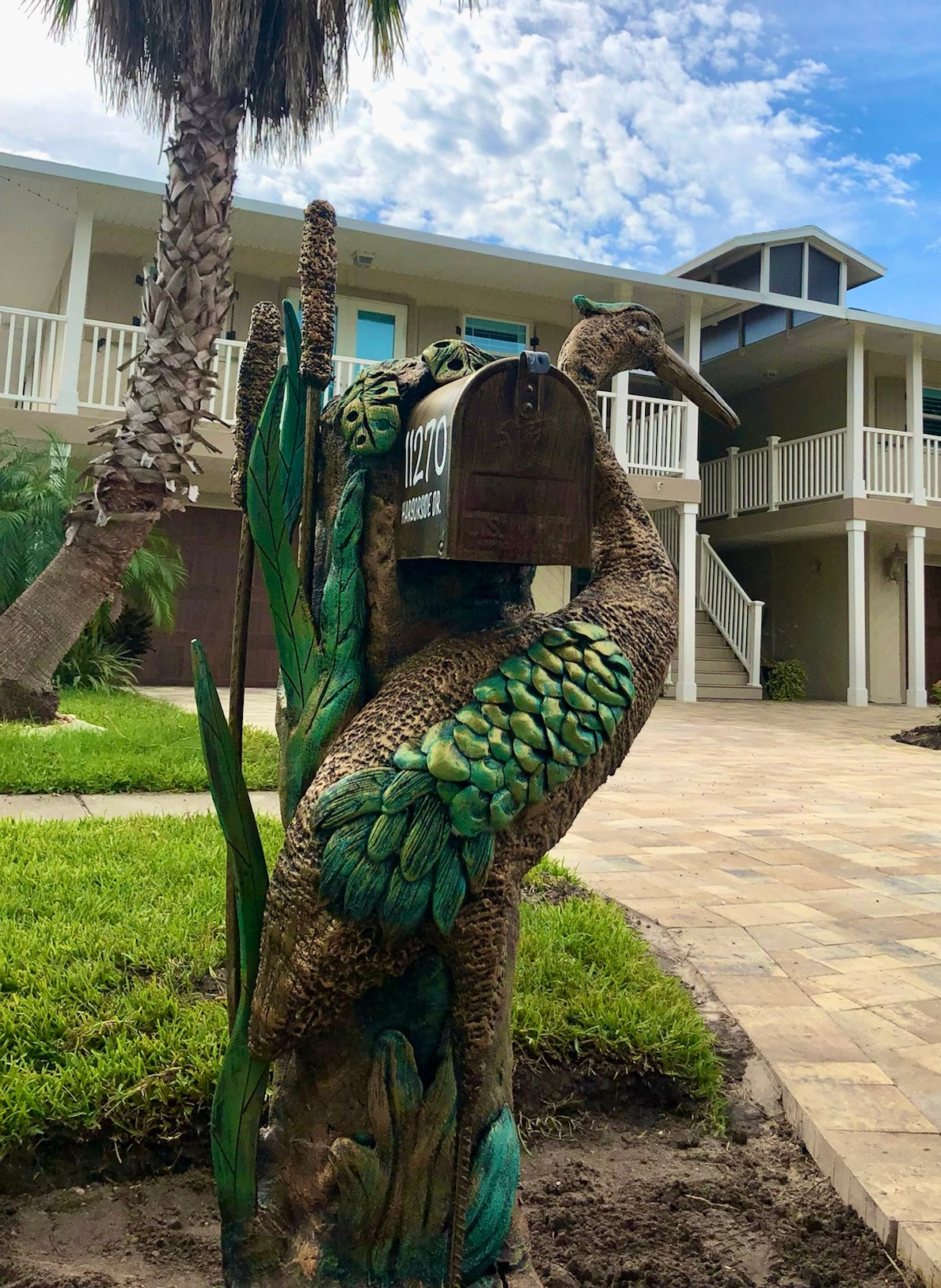Decorative mailbox shaped like a bird with a house in the background
