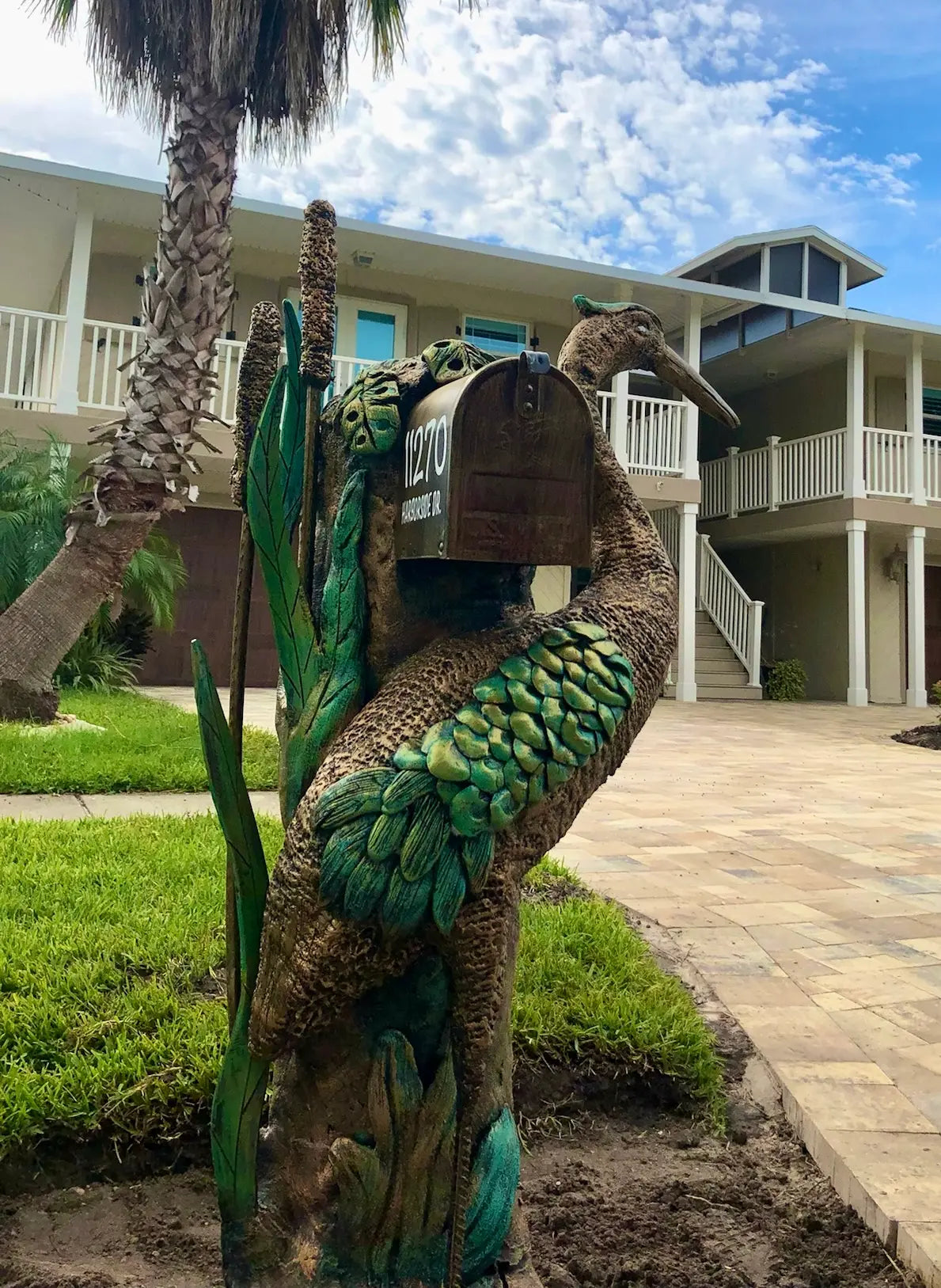 Decorative mailbox shaped like a bird with a house in the background