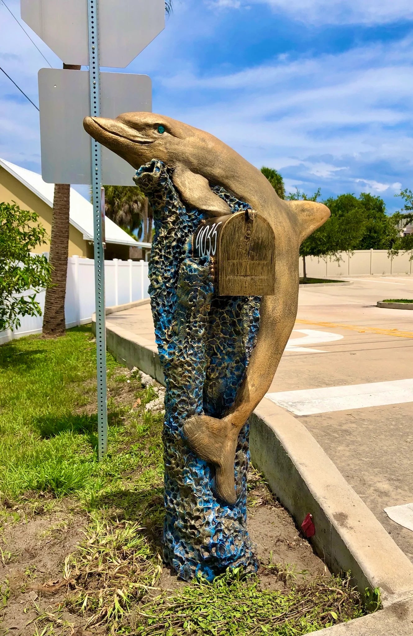 Handcrafted golden dolphin statue, turquoise blue eyes by Seaside Mailbox, nautical cement art for coastal homes.